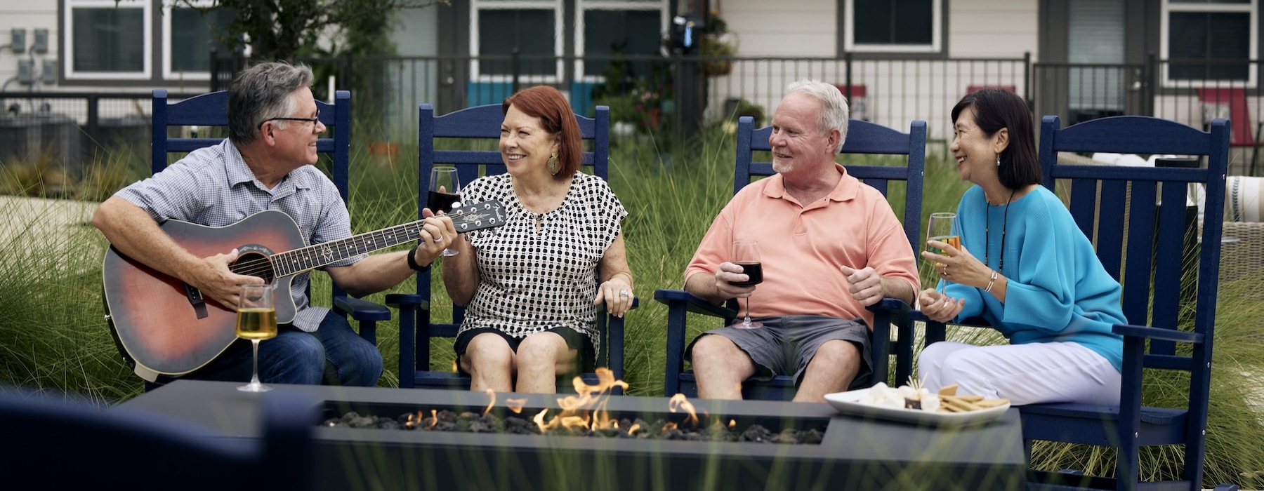 people sitting around fire and a man playing a guitar