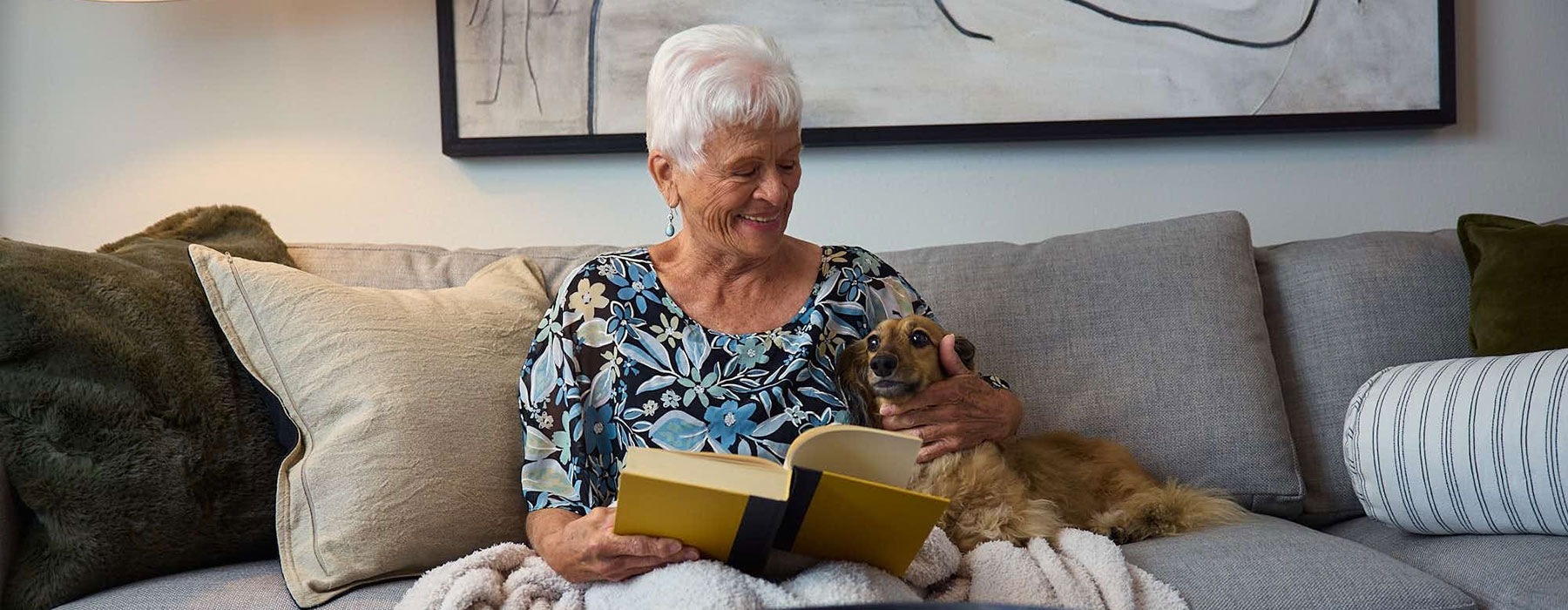 woman reading next to dog on sofa