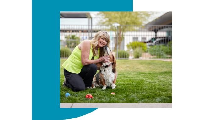 a woman kneeling down holding a dog